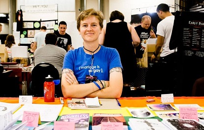 a photo of LB's vessel sitting at a comic con table, which is covered with a pride flag tablecloth and piles of home-printed comics